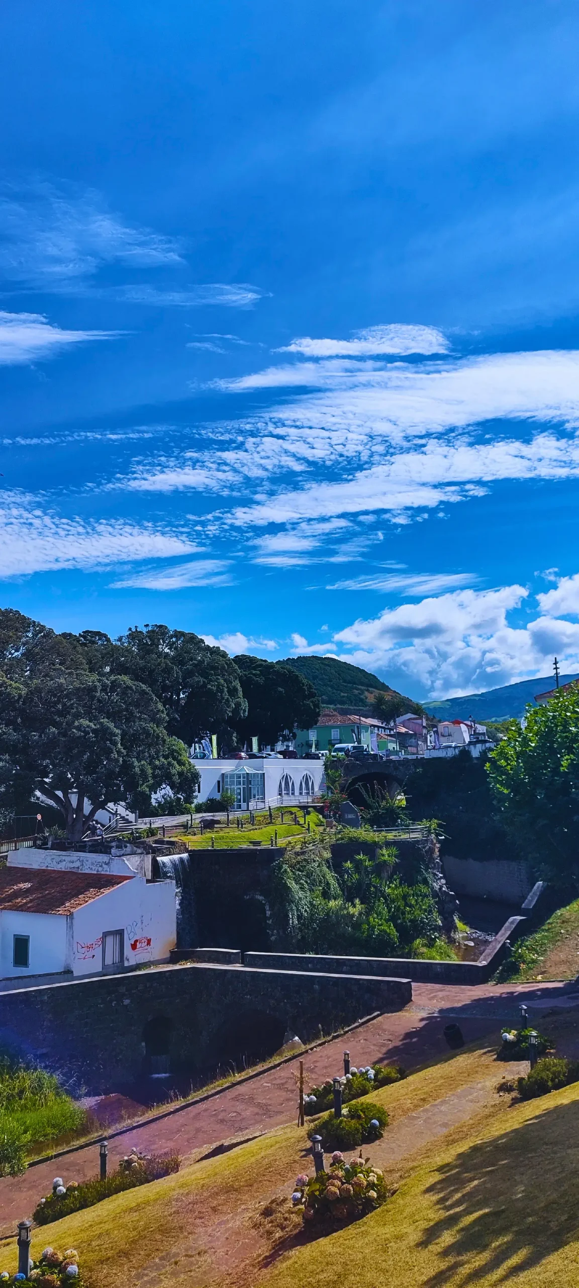 A view from a garden with houses and a stream.