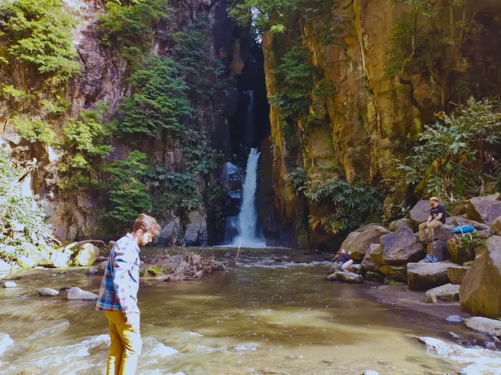 cabrito-waterfall-man A man hops around stones in front of a waterfall.