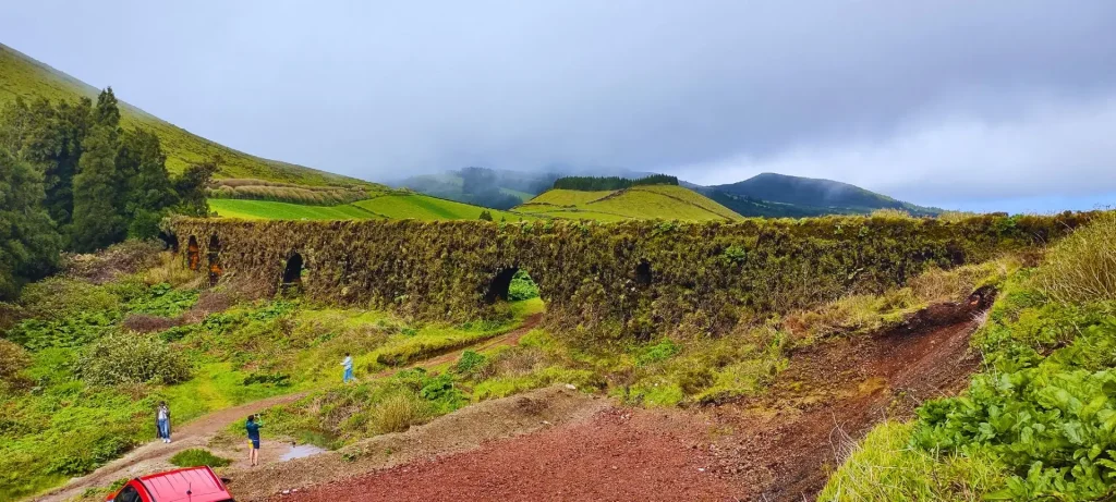 A long aqueduct covered in moss and surrounded by vegetation.