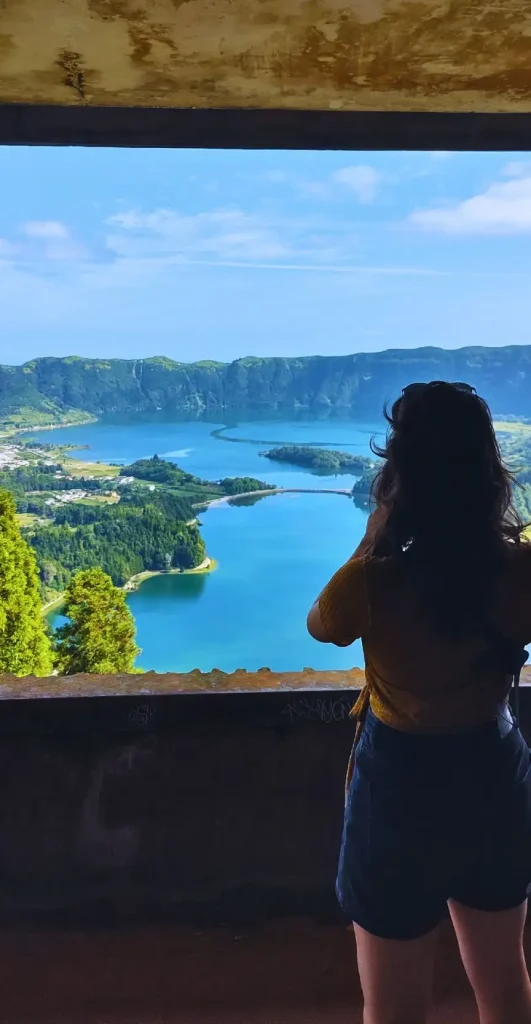 A girl looking at a big lagoon from an abandoned hotel balcony.