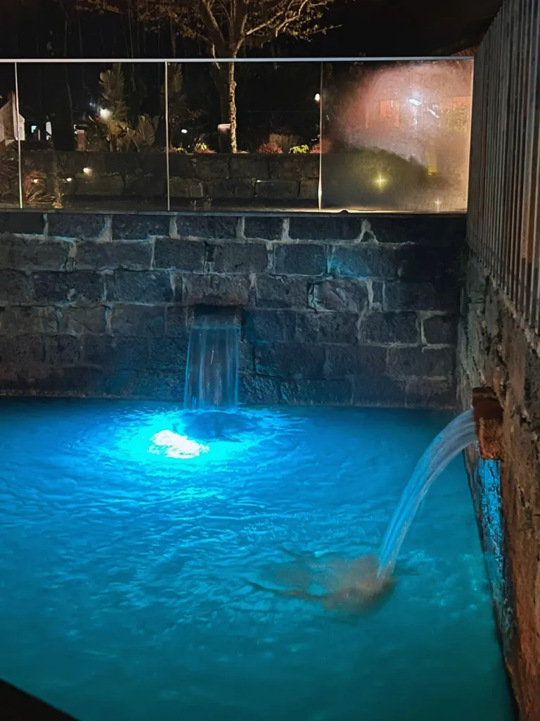 A hot spring pool at night, blue light is reflecting from inside the water.